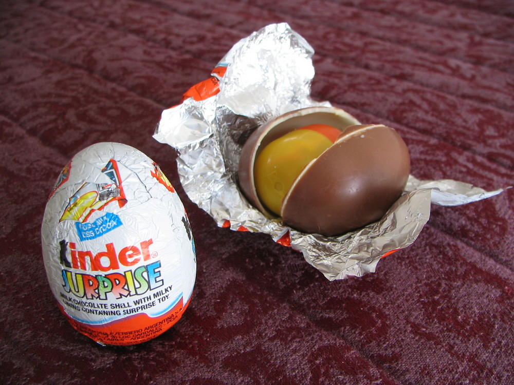 Chocolate egg, its cover, and plastic container with a toy.