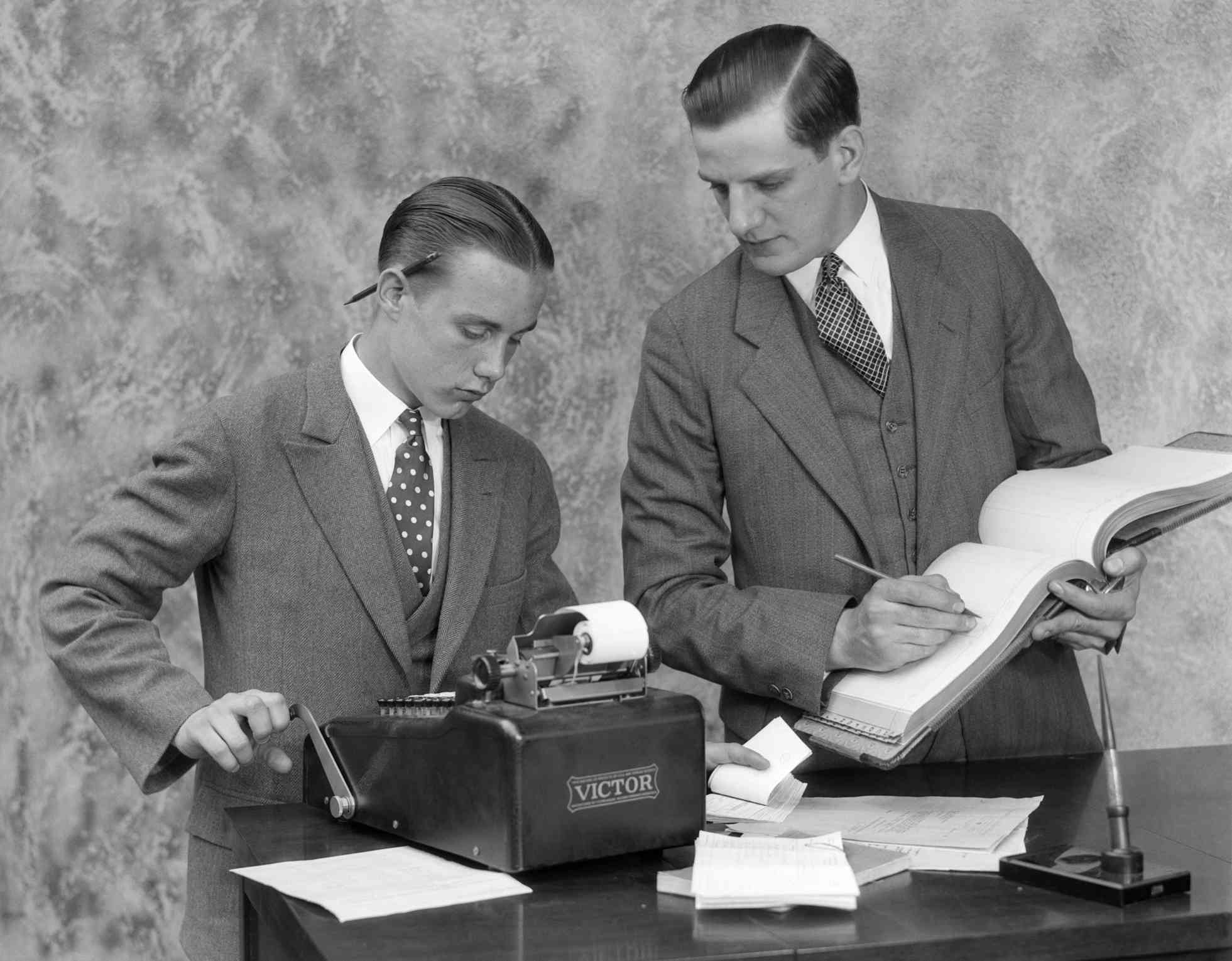 1920s Bookkeeper and assistant using a ledger book and manual adding machine, ClassicStock. The Balance. Web.